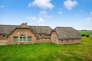 a large brick house with a thatched roof at Large Holiday Home For 20 People With Large Pool, Hot Tub For 7 People And Activity Room in Ringkøbing
