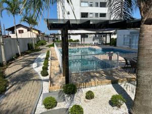 a swimming pool with a black umbrella and a building at Residencial Órion Condomínio Piscina 250m Praia in Piçarras