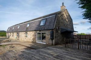 an old stone building with a fence in front of it at Woodside Barn Stunning 7 bed Barn conversion in Newmachar