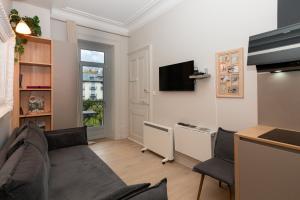 Una sala de estar con un sofá y un televisor. en Au Temps Suspendu, en Aix-les-Bains