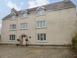 una gran casa de ladrillo con una puerta rosa en Norchard Farm House, en Tenby