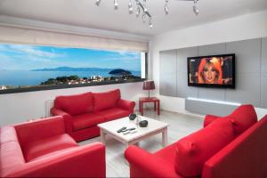 sala de estar con muebles de color rojo y ventana grande en Villa Maria Callas en PalaiónTsiflíkion