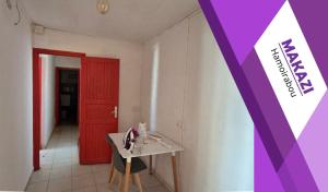 a room with a table and a red door at MAKAZI Hamoirabou in Tsingoni