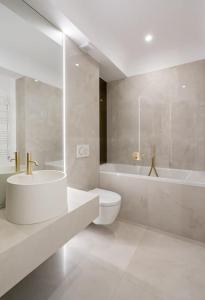 ein weißes Badezimmer mit einer Badewanne, einem WC und einem Waschbecken in der Unterkunft Ironcrest Studio - Cortina in Voluntari + 22 Fotos