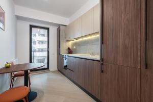 eine Küche mit Holzschränken, einem Tisch und einer Spüle in der Unterkunft Ironcrest Studio - Cortina in Voluntari