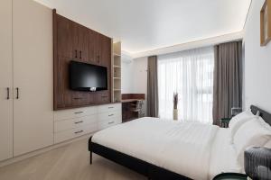 ein Schlafzimmer mit einem großen Bett und einem Fernseher an der Wand in der Unterkunft Ironcrest Studio - Cortina in Voluntari