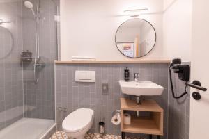 een badkamer met een wastafel, een toilet en een spiegel bij Garner Hotel Mannheim City by IHG in Mannheim