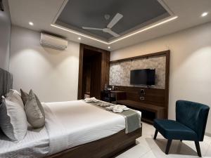 a bedroom with a bed and a chair and a television at Golden Heritage Dapoli in Dapoli