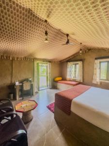 a bedroom with a bed and a couch and a table at Chokhiwadi Forest Retreat in Dogeta