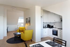 a kitchen and living room with a yellow chair and a table at Forenom Serviced Apartments Helsinki Kruununhaka in Helsinki