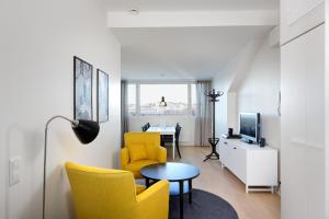 a living room with yellow chairs and a table at Forenom Serviced Apartments Helsinki Kruununhaka in Helsinki