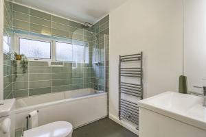 a bathroom with a tub and a toilet and a sink at The Laurels - Wifi, Parking, 4 Bedrooms, Gatwick in Crawley +32 photos