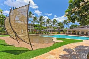 a pool at a resort with a sign in the grass at Coconut Plantation 1192-4 in Kapolei