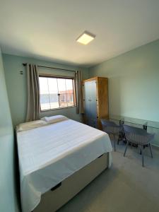 Un dormitorio con una cama y una ventana y una mesa. en Casa Solar, en Florianópolis