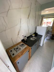 Una pequeña cocina con estufa y fregadero. en Casa Solar, en Florianópolis 7 fotos más