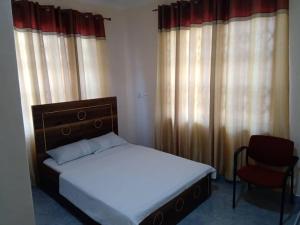 a bedroom with a bed and a chair and curtains at Alpha Rooms Single Bedroom Gome Fortress Business Center Dansoman Accra in Accra