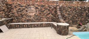 a brick wall with a bench in front at Calming Waters Guesthouse in Grahamstown