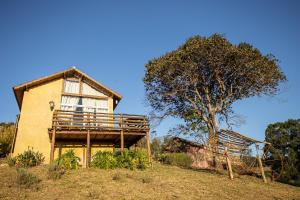 a house with a tree in front of it at Chalé Vilarejo - Vila Monte Cunha in Cunha