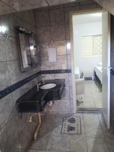 a bathroom with a sink and a mirror at Pousada Roosevelt- suíte 1 in Uberlândia