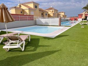 a swimming pool with a chair and an umbrella at Doral Paradise Gran Canaria in Maspalomas