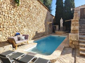 a pool in a yard with chairs and a stone wall at Casa Histórica con Piscina Sauna y Jacuzzi in Lloseta