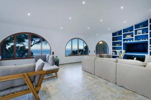 salon z białymi kanapami i telewizorem w obiekcie Maripins Villa con jacuzzi y vistas únicas al mar w mieście Banyalbufar
