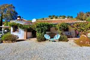 una casa con dos sillas azules delante de ella en La Perla Andaluza, en Alcaucín