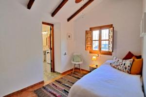Un dormitorio con una cama y una ventana y una silla. en La Perla Andaluza, en Alcaucín