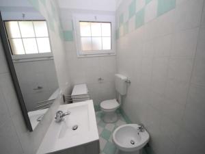 a bathroom with a sink and a toilet and a mirror at Modern flat located in Rosolina near the sea in Rosolina Mare