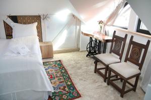 a bedroom with a bed and two chairs and a desk at Conacul Lilium in Bran