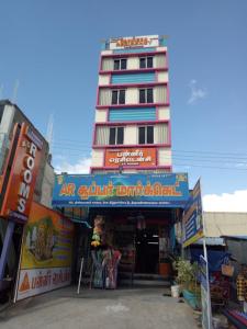 Un edificio alto con un cartel delante de una tienda. en Panneer residency, en Tiruvannāmalai