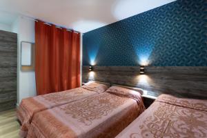 a bedroom with two beds and a blue wall at Hotel Leonard De Vinci 75011 in Paris