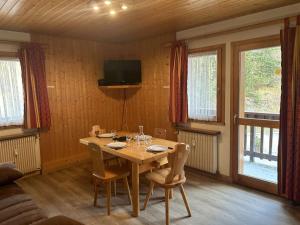 a dining room with a wooden table with chairs and a television at Appartement en montagne, 4 pers, proche des pistes et commerces, animaux acceptés, balcon, casier à skis - FR-1-180-73 in Méribel