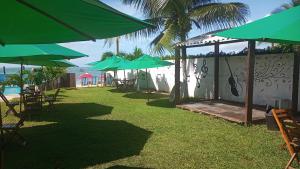 a group of green umbrellas and tables and chairs at Pousada in Porto De Galinhas