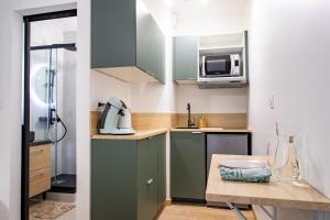 a small kitchen with green cabinets and a microwave at Nid Calme en Hypercentre - Proche Métro & Gare in Toulouse