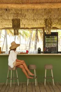 a woman in a hat sitting at a bar at Cabanas Blue in Mata de Sao Joao