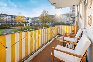 einen Balkon mit Stühlen und einem gelben und weißen Zaun in der Unterkunft EDLER WOHNRAUM Luxuriöses Apartment mit Balkon, Boxspringbett, Kaffeevollautomat, Lift & Parkplatz in Chemnitz