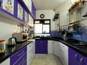 a kitchen with purple and white cabinets and a window at Calm Private Room with Beautiful View in Mumbai