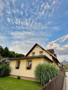 a yellow house with two windows and a fence at Chalupa Synka in Terchová