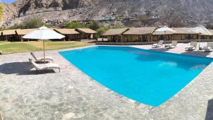 a large swimming pool with chairs and an umbrella at Aruma Codpa in Codpa