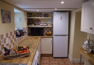 a kitchen with a white refrigerator and a bowl of fruit at Corner House in Grinton