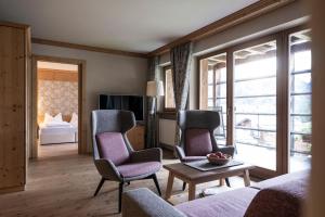 a living room with two chairs and a couch and a tv at Post Alpina - Family Mountain Chalets in San Candido +64 photos