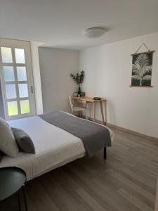 a white bedroom with a bed and a table at La Villa Bis in Vesoul