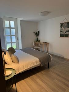 Un dormitorio con una cama y una mesa y una ventana. en La Villa Bis, en Vesoul