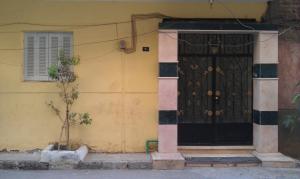 a yellow building with a black door and a window at Obelisk house in Jazīrat al ‘Awwāmīyah