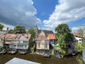 a group of buildings next to a river at goldlounge Modernes Apartment an der Krämerbrücke, Altstadt by Architekturplus und waissgold in Erfurt