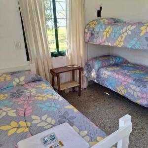 a bedroom with two beds and a table and a window at El Descanso in Villa Lía