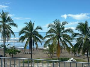 Una vista de una playa con palmeras y el océano. en OCEAN FRONT luxury hotel room "Pacific Point", en Jacó