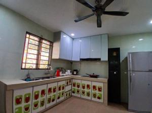 una cucina con armadi bianchi e frigorifero in acciaio inossidabile di Cartoon world homestay a Seremban