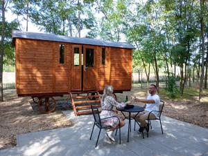 Ein Mann und eine Frau sitzen an einem Tisch vor einem winzigen Haus in der Unterkunft Alpacacamp in Helvécia